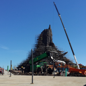 Stake out and Layout of a themed mountain structure, with scaffolding and crane on a bright day.